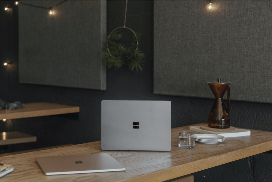image of a laptop sitting in a dimly lit office on a wood desk
