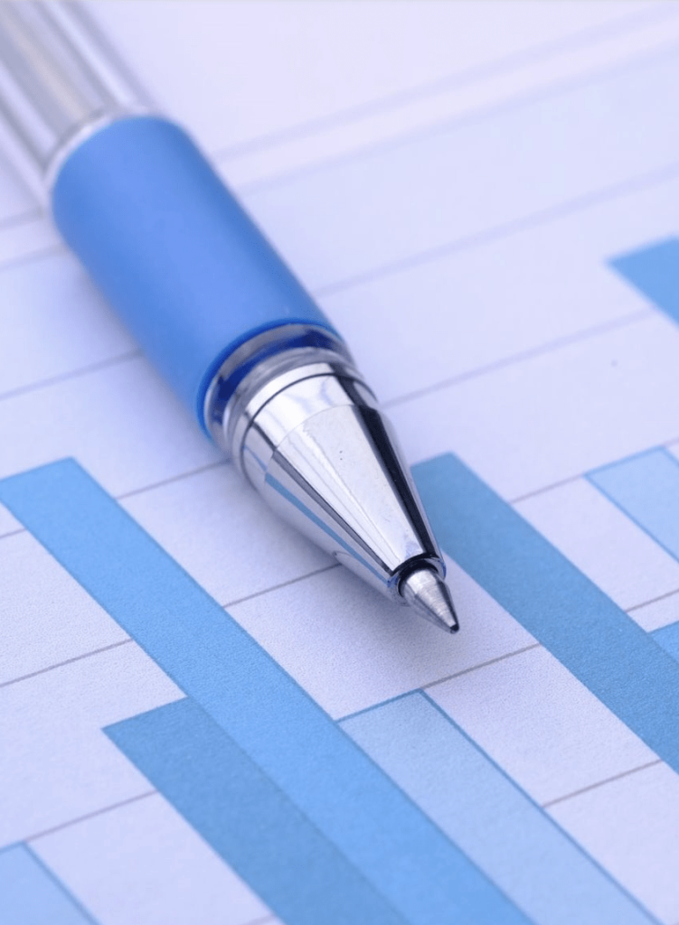 Close-up of a blue pen resting on a financial bar chart, representing data analysis and business reporting