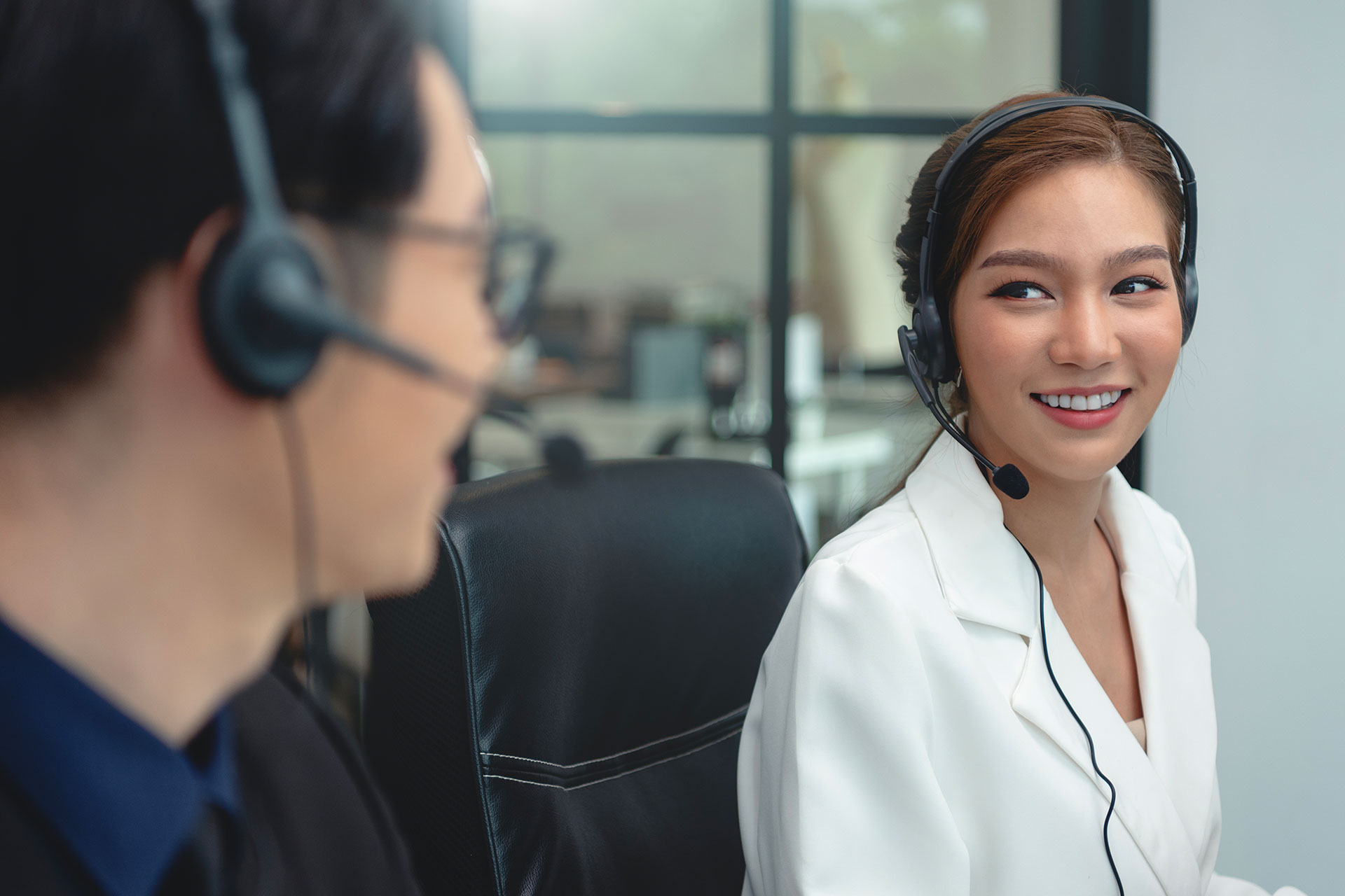 Customer support representatives wearing headsets collaborating in a modern office environment