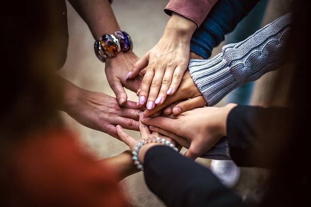 Group of people placing their hands together in a gesture of teamwork and unity