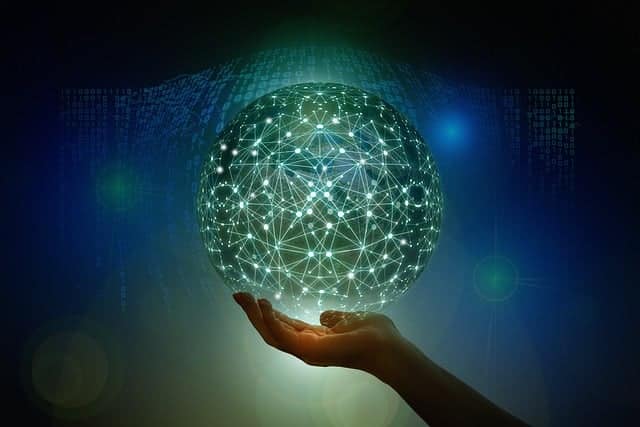 Hand holding a glowing digital globe made of connected nodes and lines, representing global technology and data networks