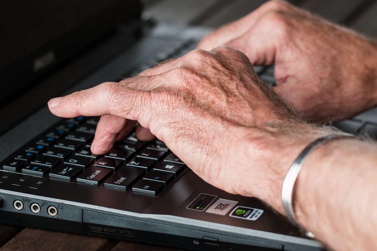 Close-up of hands typing on a laptop keyboard.
