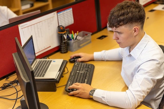 Person working at a desk using a computer and keyboard in an office setting.