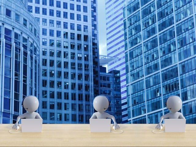 Three stylized human figures using laptops at a desk with modern office buildings in the background.