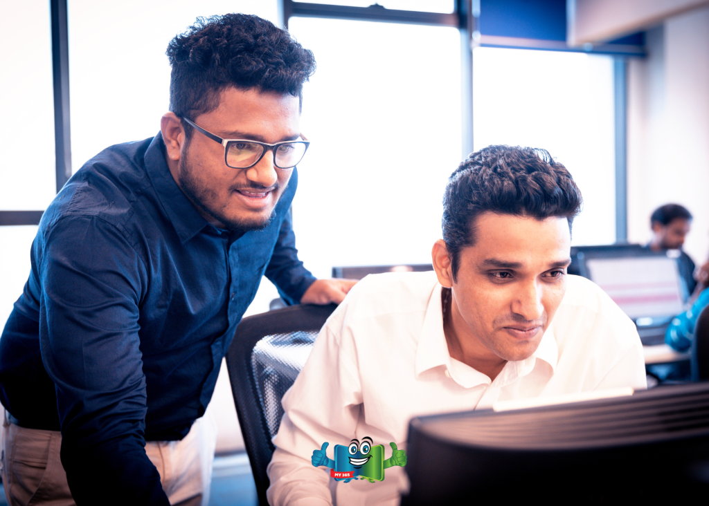 Two coworkers reviewing information on a computer screen in an office.