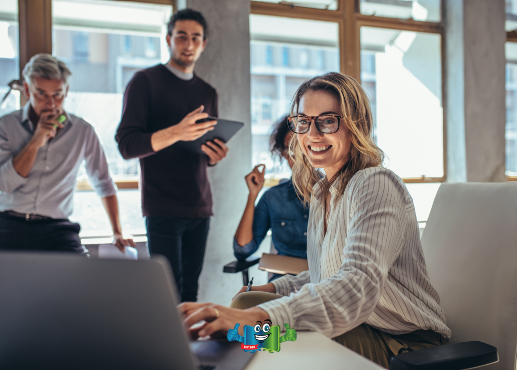Team collaborating around a laptop in a bright, modern office.
