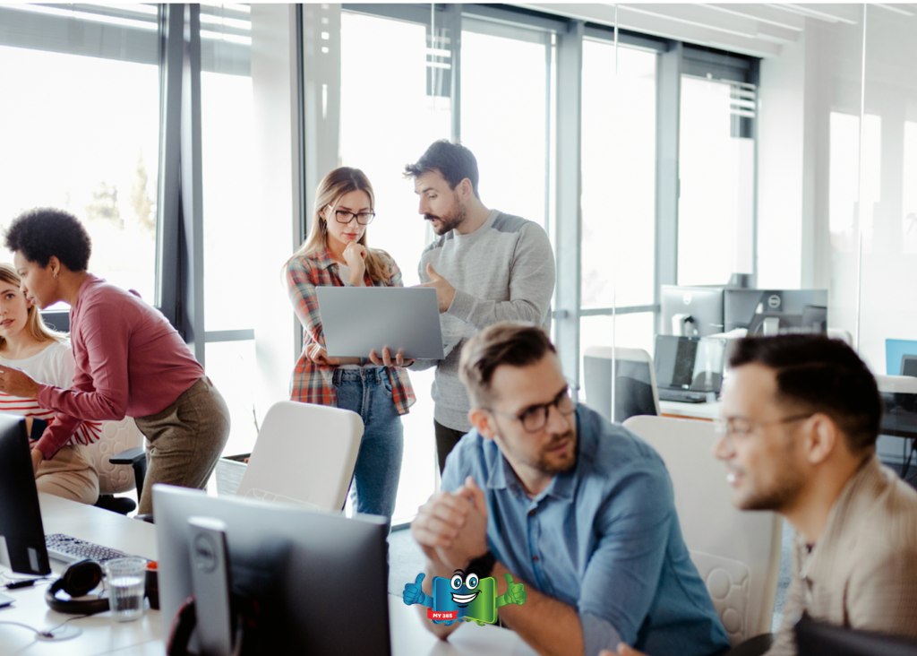 Team members collaborating around a laptop in a modern office environment.