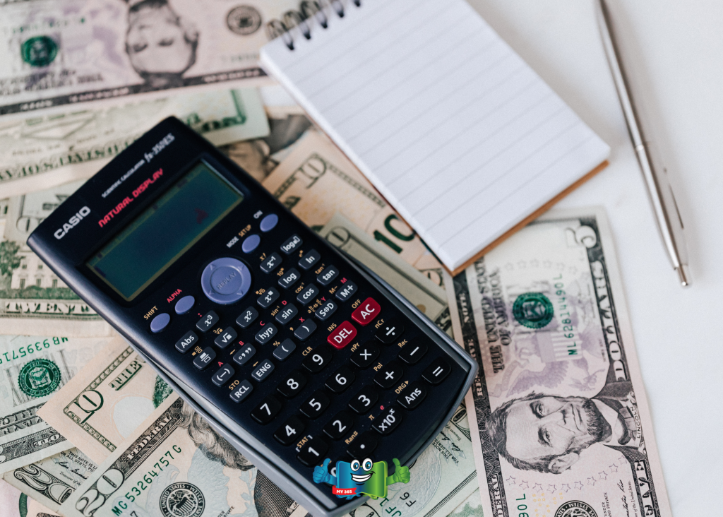 Calculator resting on U.S. dollar bills next to a notepad.