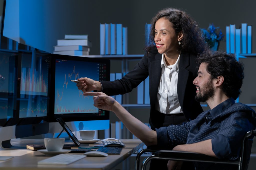 business men and women who are working hard Working late into the night to complete tasks according to set goals The two of them looked at the company's financial graph attentively.