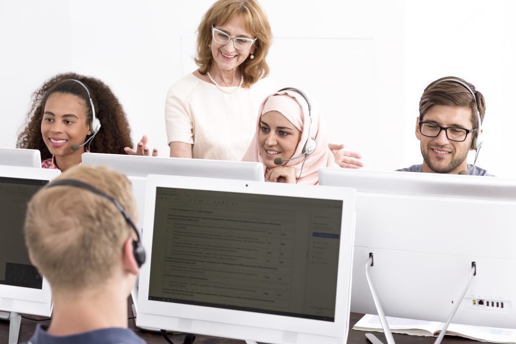 Customer support team wearing headsets while a supervisor provides guidance.
