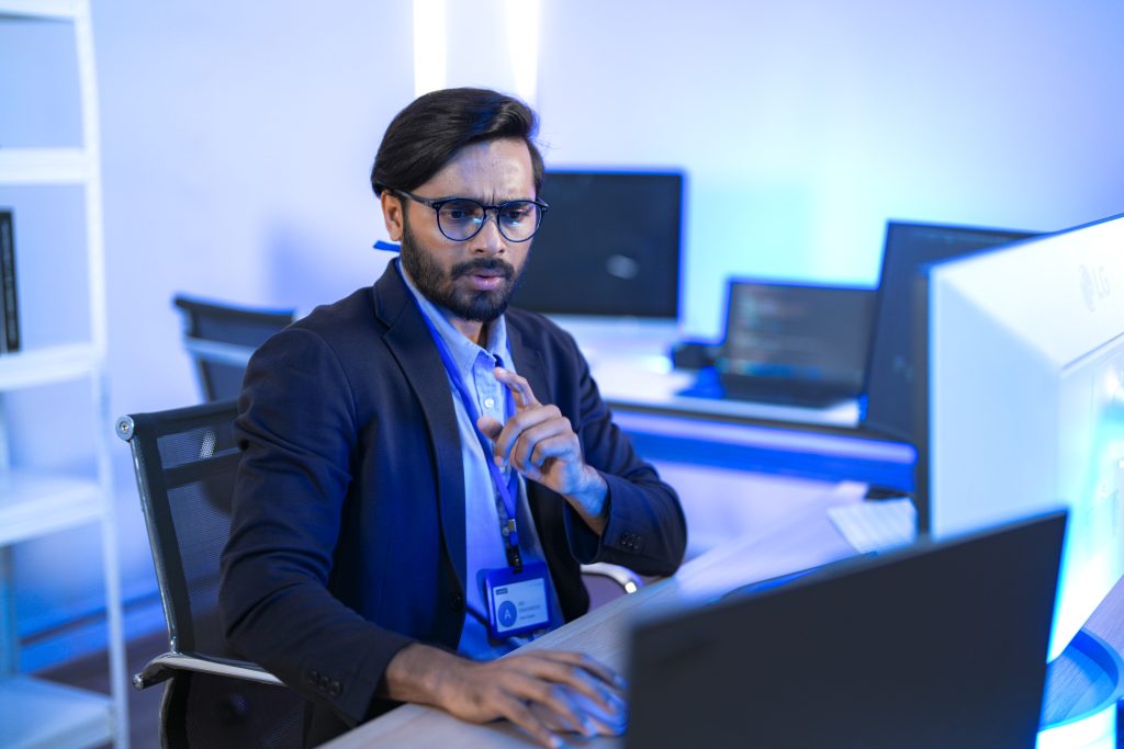 Stressed IT professional reacts with shock to a critical system error on his computer. A developer discovers a major bug or a cybersecurity threat, expressing concern.