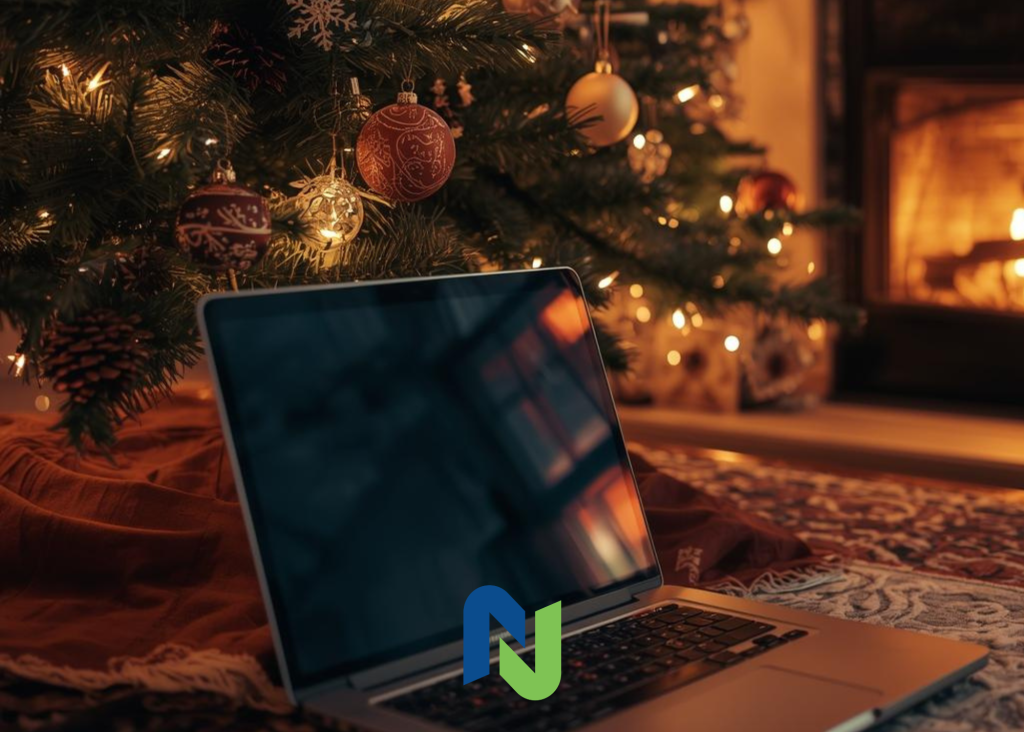Laptop on a rug beneath a decorated Christmas tree with warm lights and a fireplace in the background.
